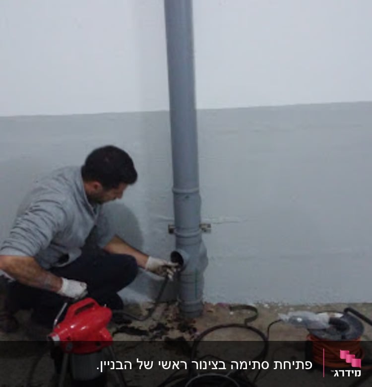 אדם עובד על צינור ביוב עם כלים